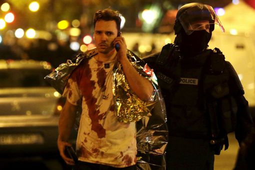 A French policeman assists a blood-covered victim near the Bataclan concert hall 