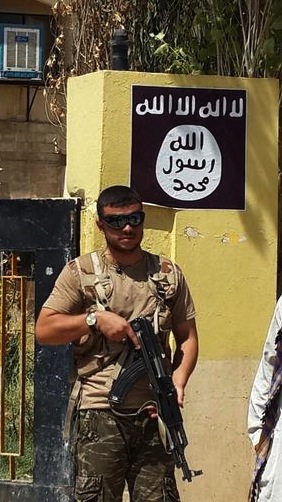 A fighter with the Islamic State group stands guard in front of the headquarters of the Kurdistan Democratic Party (KDP) in the Christian village of Bartella, northern Iraq, Thursday, Aug. 7, 2014. (AP Photo)