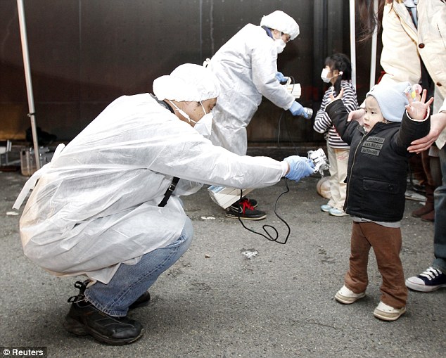 Precaution: Officials in protective gear check today for signs of radiation on children who are from the evacuation area near the nuclear plant