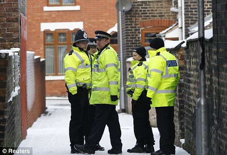 Raids: Police officers stand outside a house in Stoke-on-Trent, one of several raided in England and Wales during the 5am operation