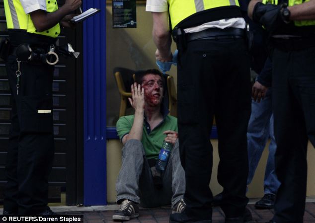 British Police officers speak to an injured man after a right wing demonstration sparked violence in Birmingham